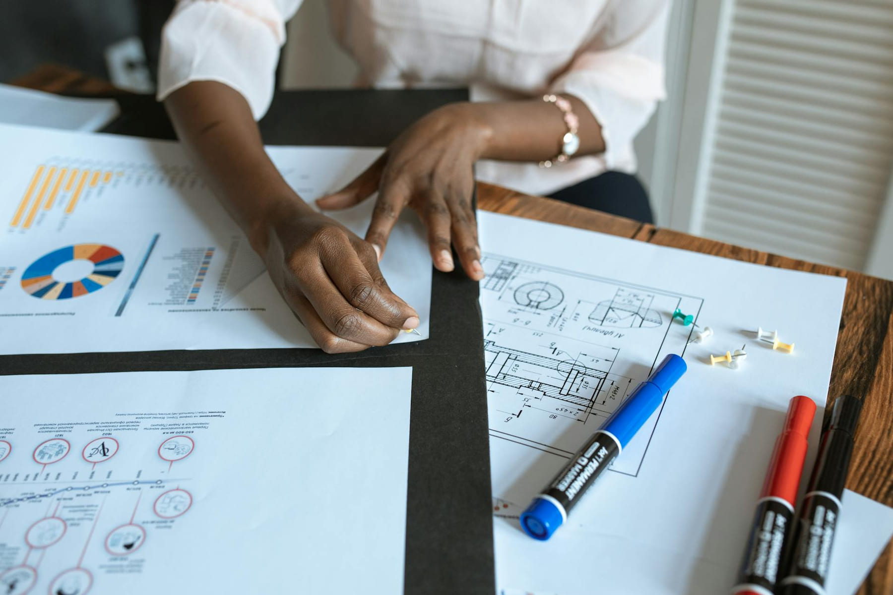 An adult working on business charts and design blueprints in an office setting. on Small Biz Blueprint