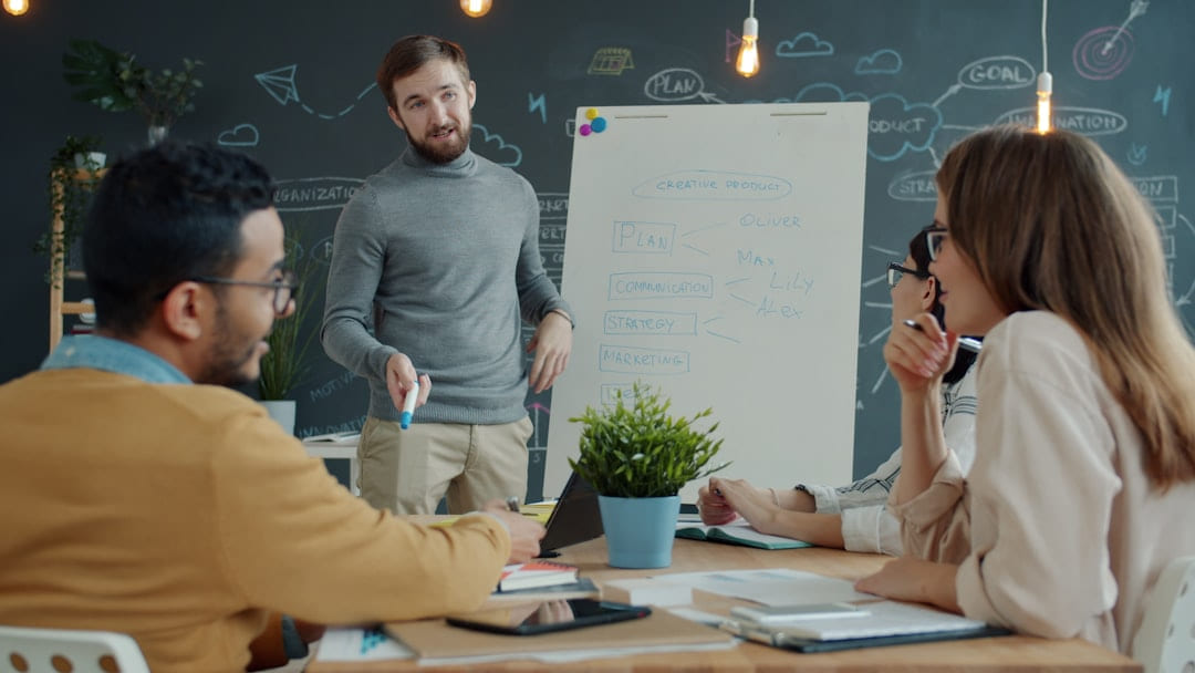 Team collaborating around a whiteboard during a meeting. on Small Biz Blueprint