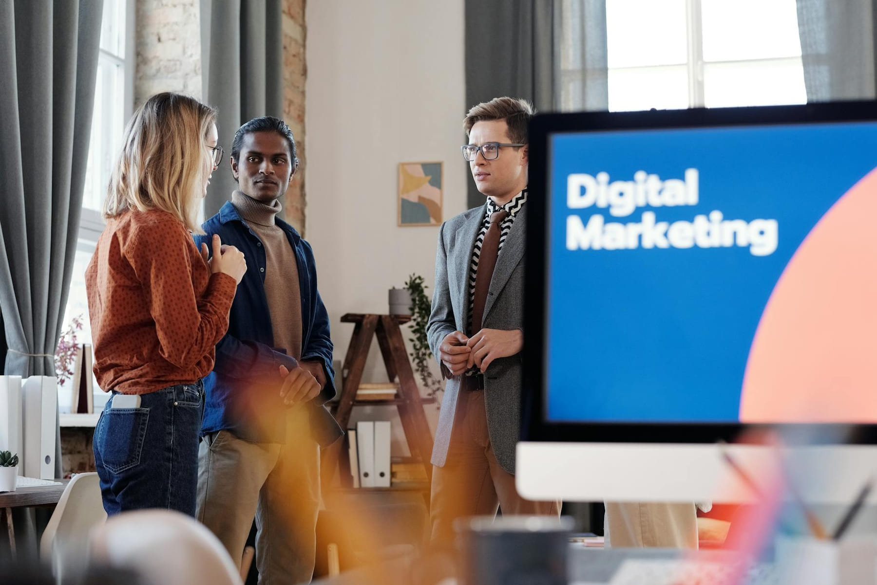 Group of colleagues discussing digital marketing strategies in an office setting. on Small Biz Blueprint