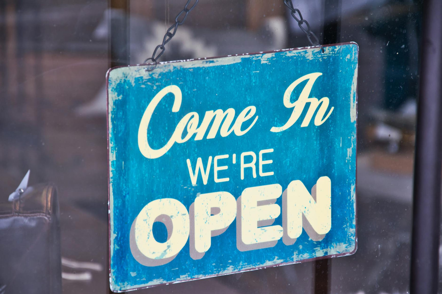 Retro blue open sign on a shop glass door inviting customers in. on Small Biz Blueprint