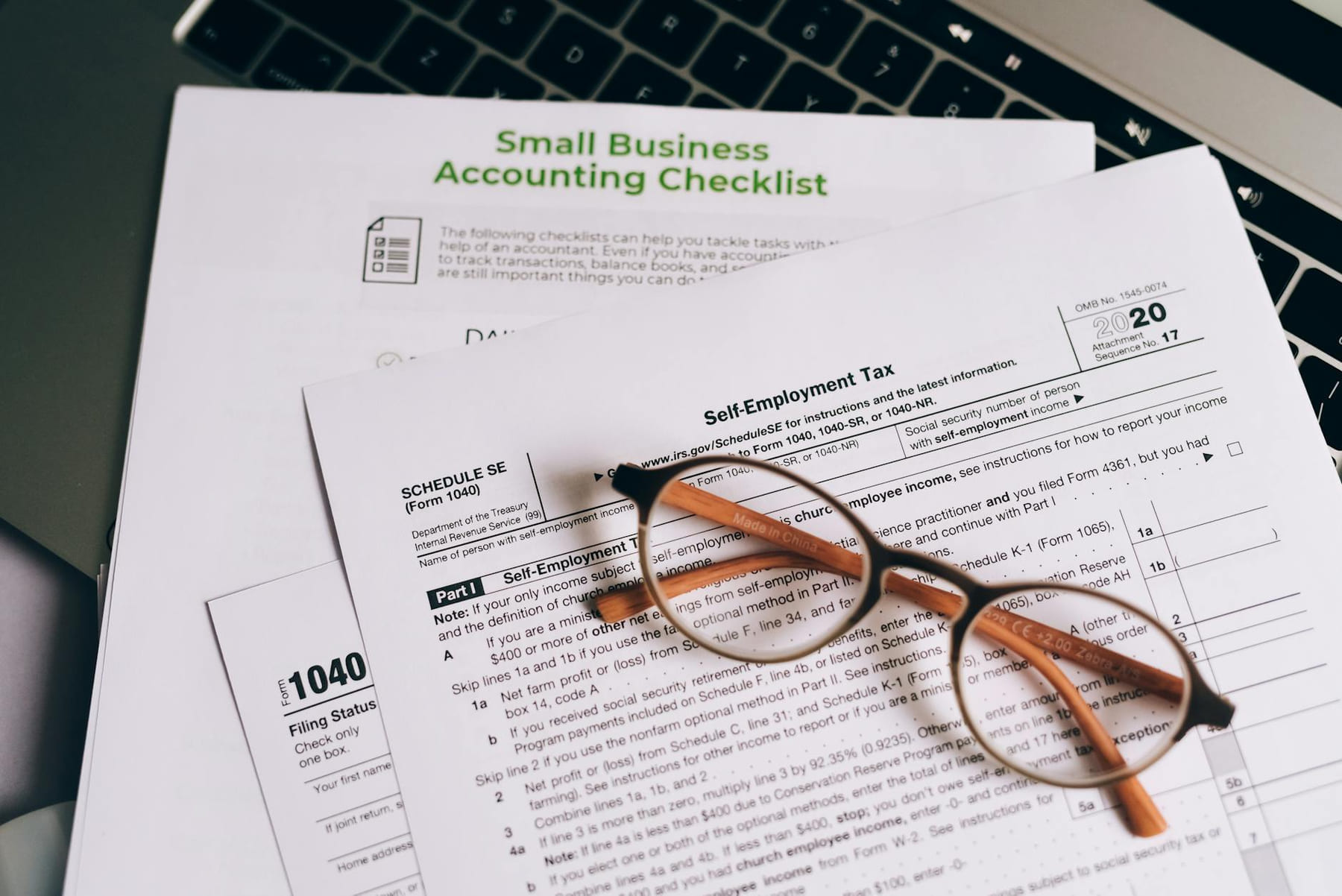 Close-up of tax forms and a small business accounting checklist on a laptop. on Small Biz Blueprint