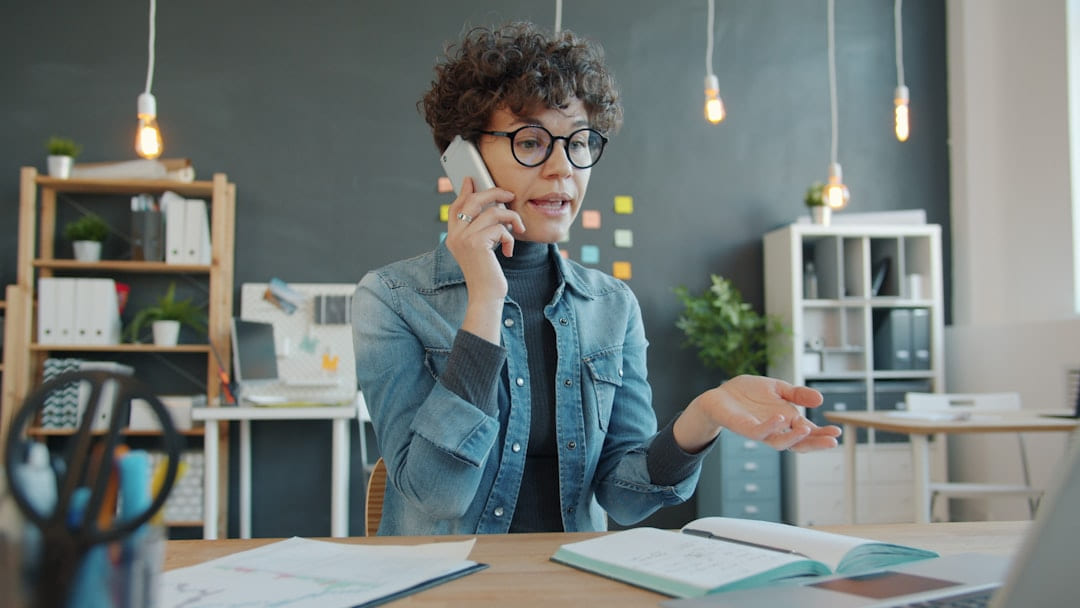Woman talking on phone at desk in office on Small Biz Blueprint