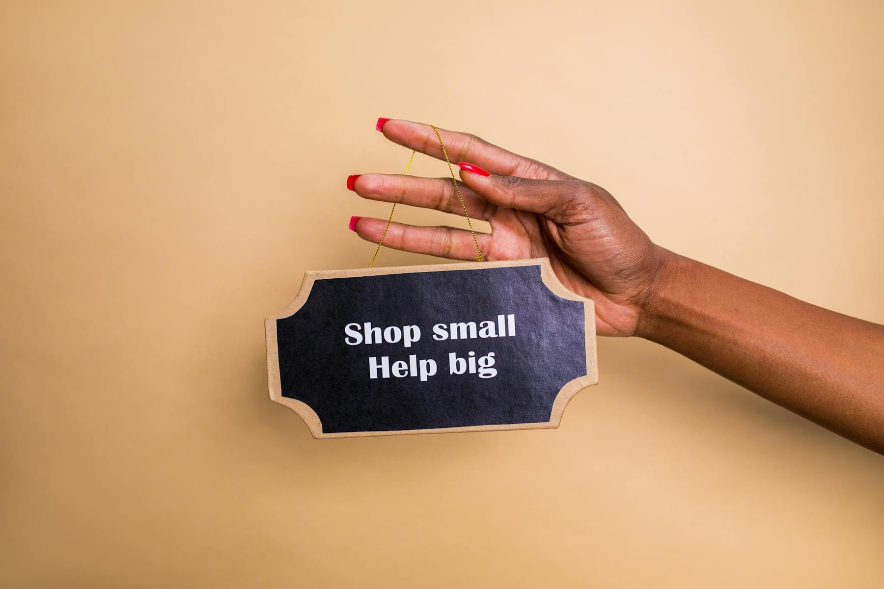 Close-up of a hand holding an inspiring sign encouraging small businesses support. on Small Biz Blueprint