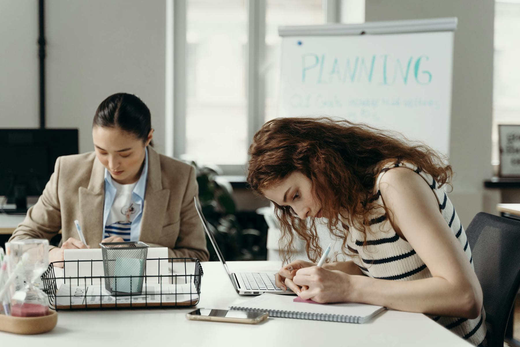 Two businesswomen working intently on planning projects in an office setting. on Small Biz Blueprint