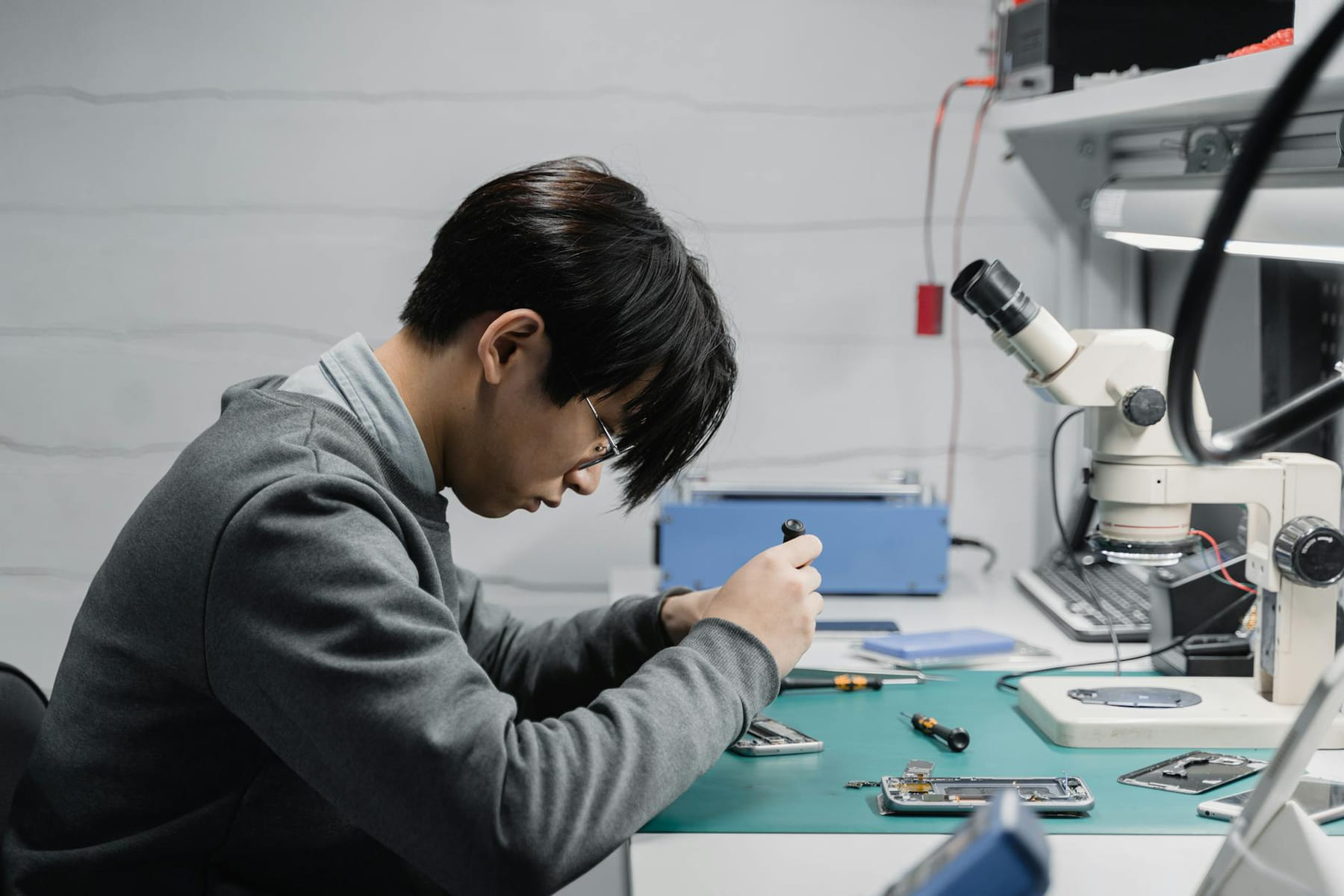 Professional technician repairing mobile devices using a microscope in a lab. on Small Biz Blueprint