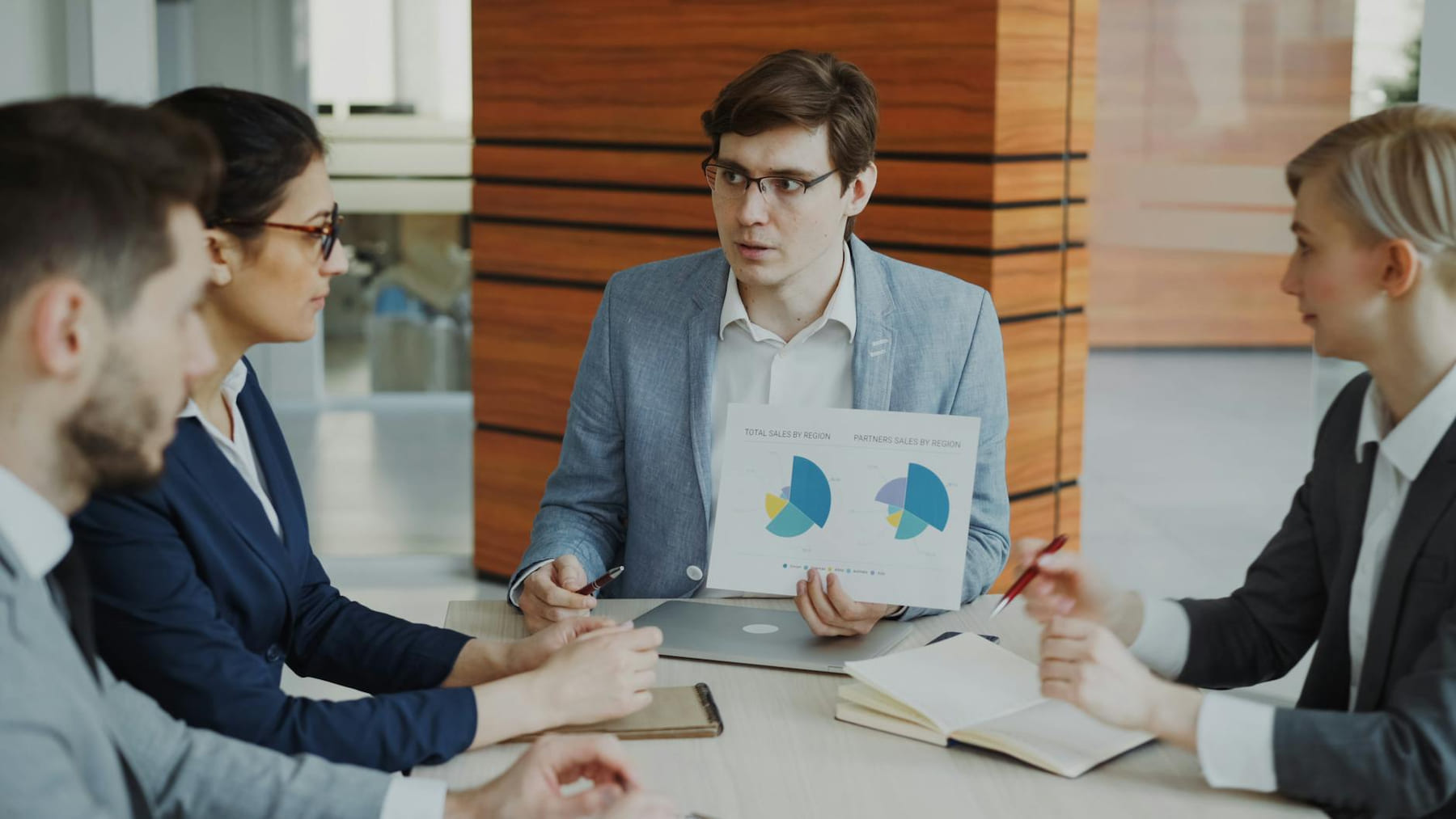 A team engaged in a business meeting discussing charts and strategies in an office. on Small Biz Blueprint