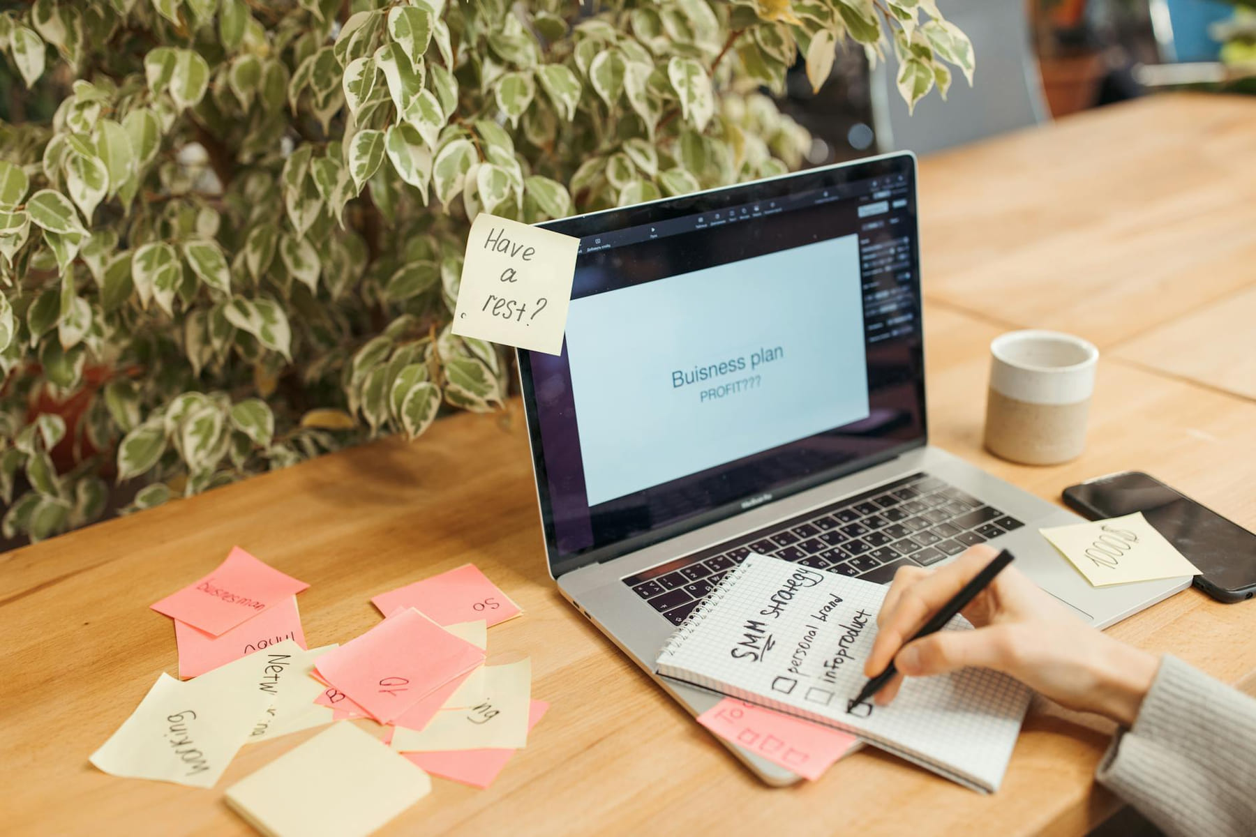 A workspace with a laptop, sticky notes, and a notepad for business planning. on Small Biz Blueprint