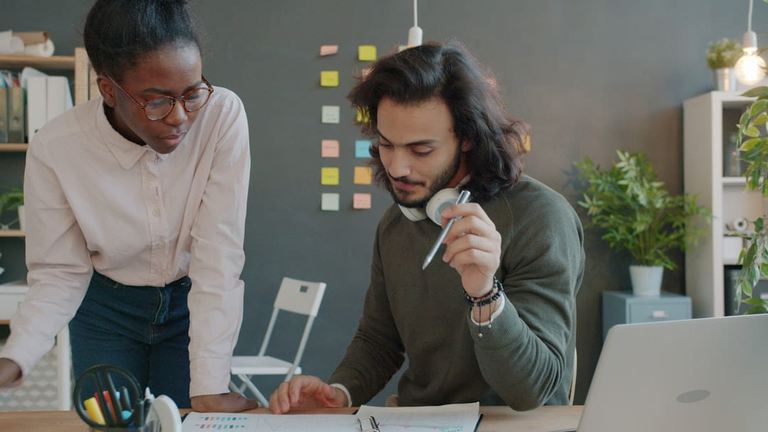 Two colleagues collaborating at a desk in an office. on Small Biz Blueprint